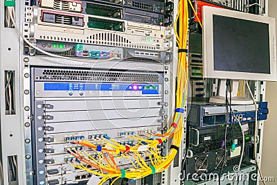 Rack with powerful Internet servers. The monitor is installed in a computer cabinet. A central router with multiple optical cables Stock Photo