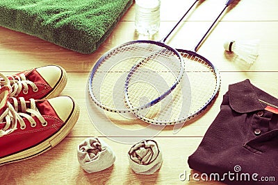 Rackets for badminton, shuttlecock, polo shirts, shoes, towel and water on a wooden floor Stock Photo