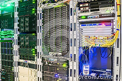 Racks with servers are installed in the server room of the data center. Multiple optical wires connect to the central router. The Stock Photo