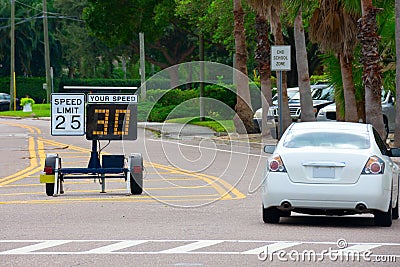 Radar speed limit indicator sign showing 30 proving a passing car is speeding as it drives down the road in a school zone Stock Photo