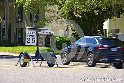 Radar speed limit indicator sign showing a passing car is speeding as it drives down the road Stock Photo