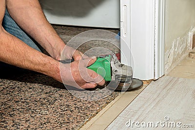 Radial grinder held by the hand with two amputated fingers of a person while he works laying floor in his house. Physical disabili Stock Photo