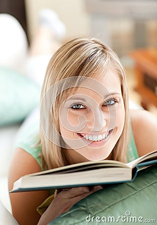 Radiant woman lying on a sofa reading a book Stock Photo