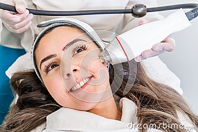 Radio frequency microneedling machine handpiece on the cheek of a woman`s face during a beauty skin tightening treatment Stock Photo