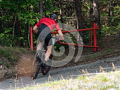 Cyclist goes through open gate bar into terrain in forest Editorial Stock Photo