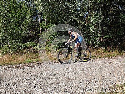 Sportsman with compressing tights brakes before turn in forest Editorial Stock Photo