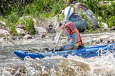 Rafting, kayaking. Young girl sailing on a rubber inflatable boat in a stormy stream of water. Water splashes close-up. Editorial Stock Photo