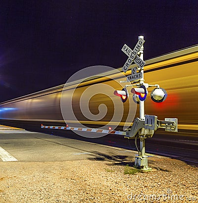 Railroad crossing with passing train by night Stock Photo