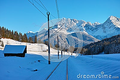 Railroad line and barns in alpine landscape by blue sky Stock Photo