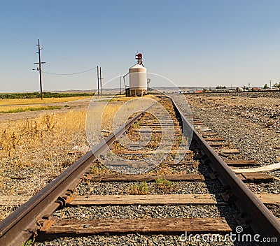 Railroad tracts lead to granary to collect grain for transport Stock Photo