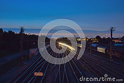 Rails and passing train at night Stock Photo