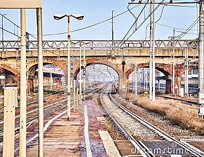 Railway with catenaries crossing a bricks bridge in an European train station Stock Photo