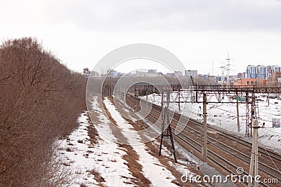 Railways leading up to the perspective to the city in the far away background. Leafless trees are on the side of the tracks and Stock Photo