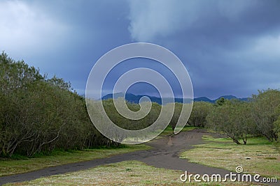 Rain clouds on bifurcation of dirt road in Etna Park Stock Photo