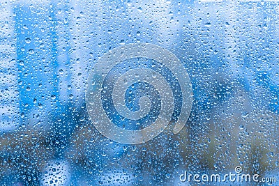 Rain drops on the glass window. night rainy window in autumn spring summer. abstract natural view. rainy season. droplets on blue Stock Photo