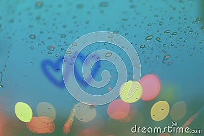 Rain drops and two hearts write on window with light bokeh. Stock Photo