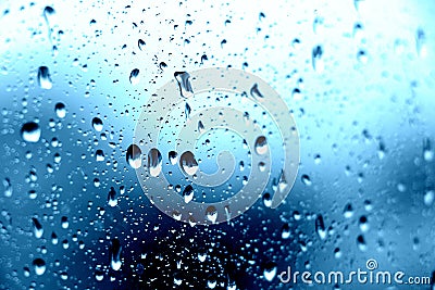 Rain. Drops on the window. Close on the glass. Shower. Wet glass. Blue background. Stock Photo