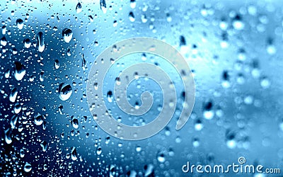 Rain. Drops on the window. Close on the glass. Shower. Wet glass. Blue background. Stock Photo