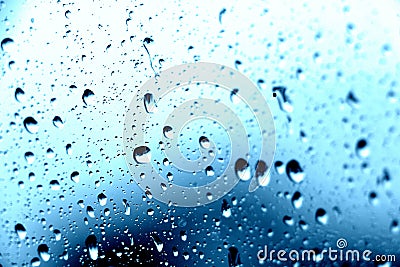 Rain. Drops on the window. Close on the glass. Shower. Wet glass. Blue background. Stock Photo