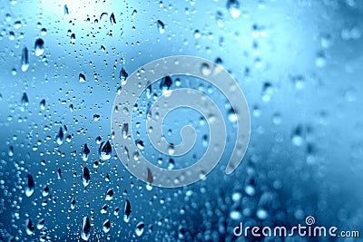 Rain. Drops on the window. Close on the glass. Shower. Wet glass. Blue background. Stock Photo