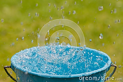 Rain falling into full bucket Stock Photo