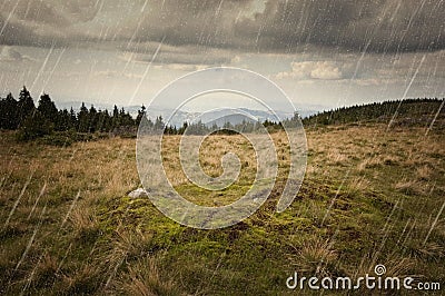 Rain falling over mountain meadow landscape Stock Photo
