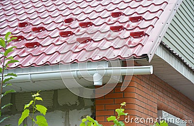 Rain gutter downspout drain pipe installation with metal roof snow board protection Stock Photo