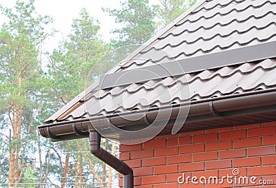 Rain Gutter Pipeline System Installation. Roofing Construction. Rain gutter system and roof protection from snow Snow guard. Stock Photo