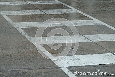 Rain at a row of white liraining at a white lines of crosswalk on city stree.The rainy season Stock Photo