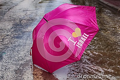 Rain, Winter Weather in Israel. Umbrella with the caption I love Israel inside the puddle Stock Photo