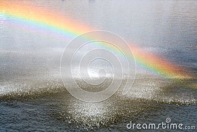 Rainbow above water surface. Rainbow from city fountain splash water drops Stock Photo