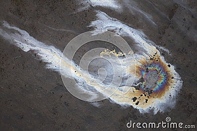 Rainbow colored comet shaped oil spill on polluted dark concrete. Stock Photo