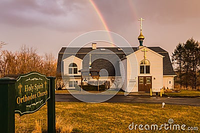 A rainbow emerges over church after a very warm day and afternoon rain Editorial Stock Photo