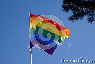 Rainbow flag with blue sky background - LGBT symbol - for gay, lesbian, bisexual or transgender relationship, love or sexuality Stock Photo