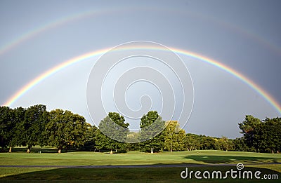 A rainbow with many shades of blue over a golf course Stock Photo