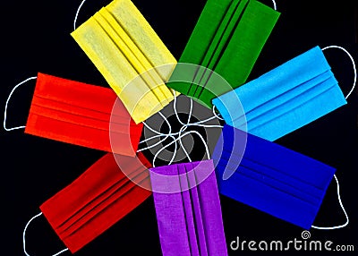Rainbow of medical masks on a black background.Seven multi-colored masks. Stock Photo