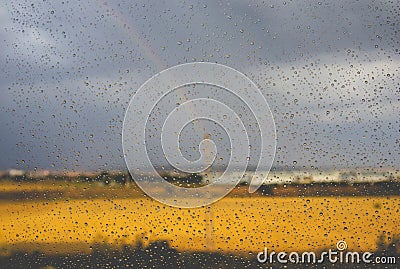 Rainbow outside a window rainy day Weather forecast. Raindrops on window surface Stock Photo