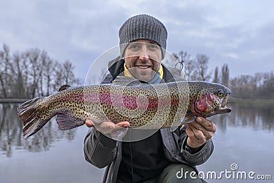 Rainbow trout fishing. Fisherman with motley salmon fish at area pond Stock Photo