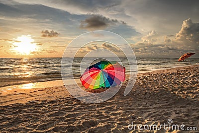 Rainbow umbrella on White sand at Delnor Wiggins State Park at sunset Stock Photo