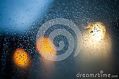 Raindrops on the glass of a window before the blurred lights - blue relaxing background Stock Photo