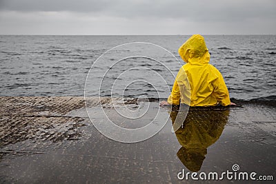 Rainy clouds. Child in a yellow raincoat. Stock Photo