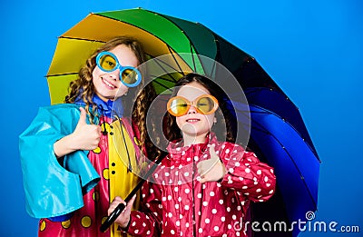Rainy weather with proper garments. Walk under umbrella. Kids girls happy friends under umbrella. Bright umbrella. Happy Stock Photo