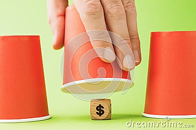 Raised glass and wooden cube with dollar symbol underneath, thimble gambling concept Stock Photo