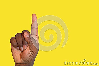 Raised hand asking for permission or answering a question on a yellow background - African ethnicity Stock Photo