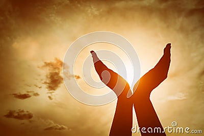 Raised hands catching sun on sunset sky. Concept of spirituality, wellbeing, positive energy Stock Photo
