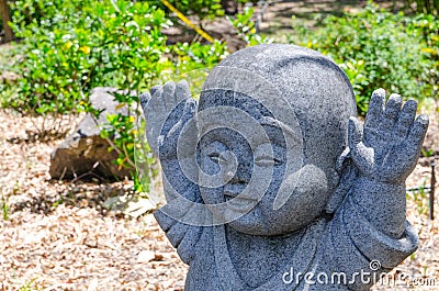 Raised hands up motion of Jizo little stone buddha statue. Stock Photo