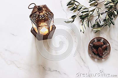 Ramadan Kareem greeting card, invitation. Bronze plate with dates fruit, olive branches and glowing Moroccan lantern on Stock Photo