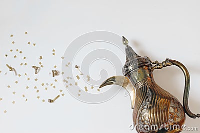 Ramadan Kareem still life. Traditional ornamental arabic dallah coffee pot with bursting golden star confetti isolated Stock Photo