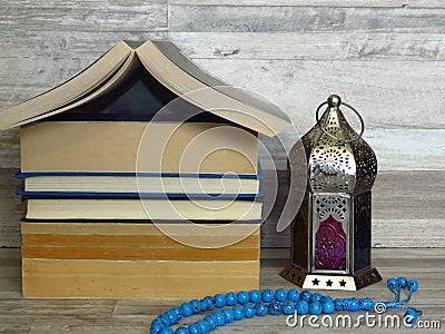 Ramadan Ramazan time celebration. A pile of home shaped old books, silver Ramadan lantern, blue turquoise chaplet, worry-beads. Stock Photo