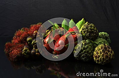 Rambutan mangosteen dragonfruit banana and custard apple in black background Stock Photo